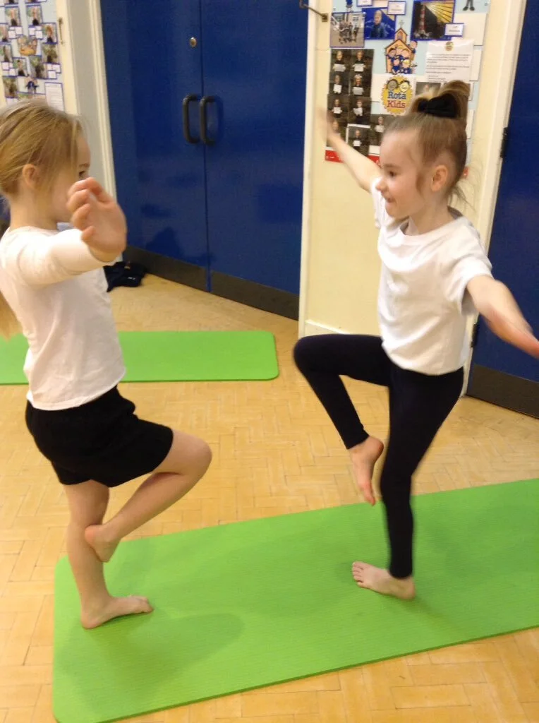 Primary school pupils doing partner yoga and balance work in Wigan