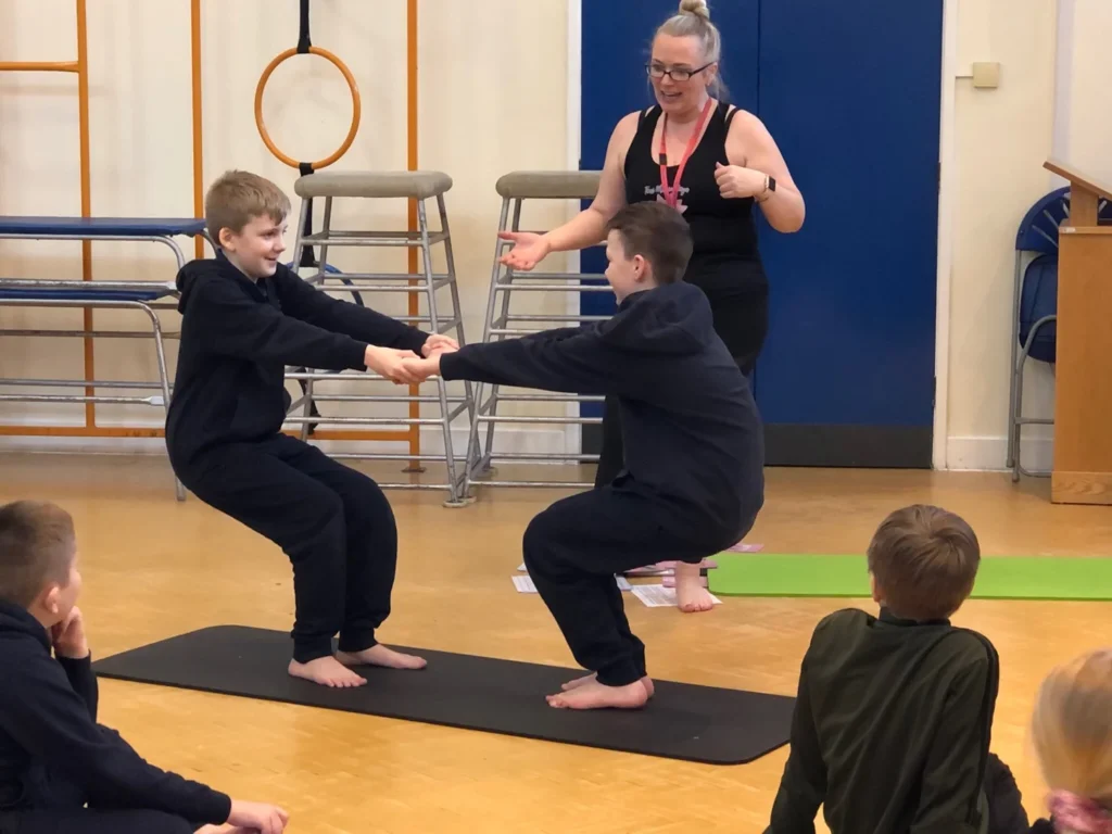 Primary school pupils doing partner yoga and balance work in Atherton