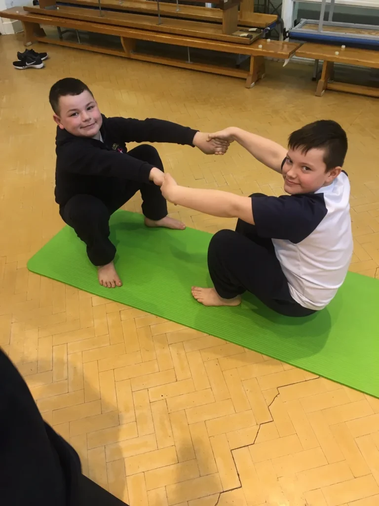 Pupils exploring simple yoga stretches and breathing exercises during a wellbeing class in Greater Manchester