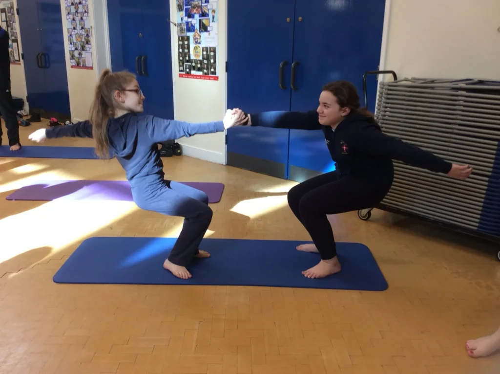 Children practising partner balance poses during a school yoga session in Bolton