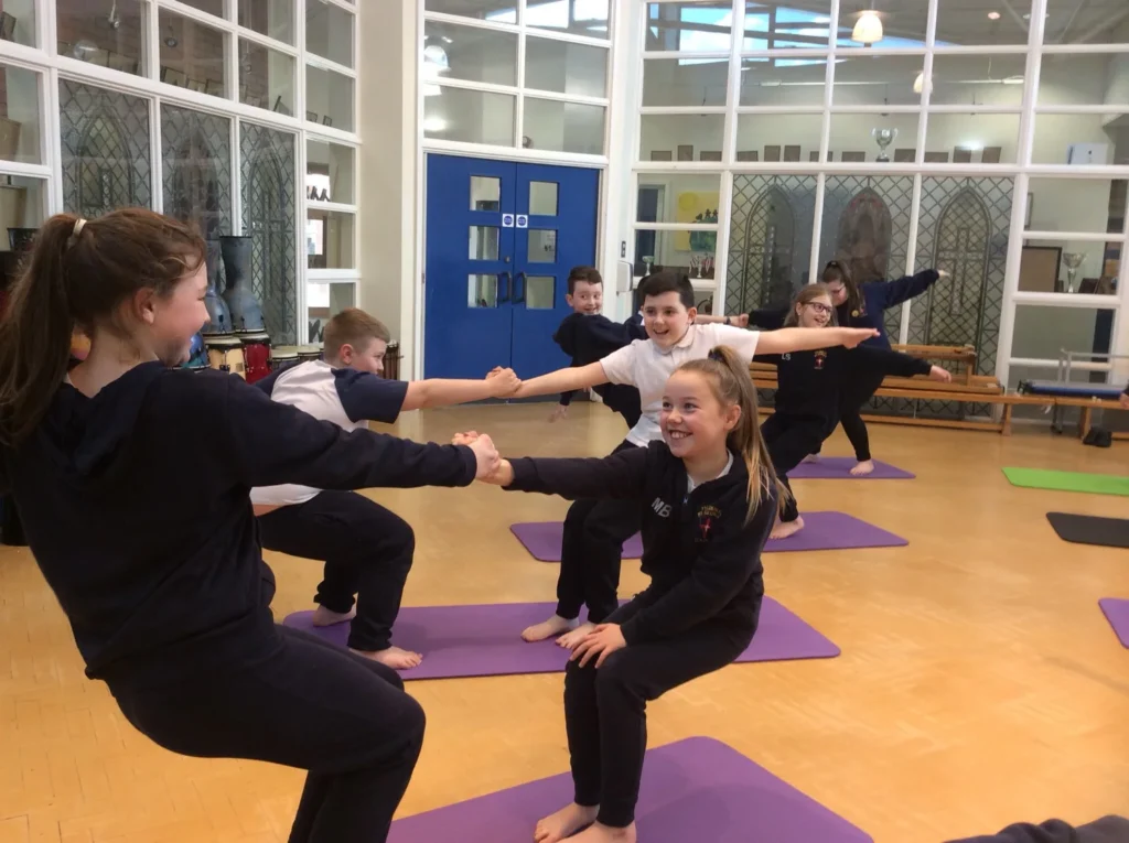 Pupils working together on partner yoga and coordination exercises during a wellbeing lesson in Atherton